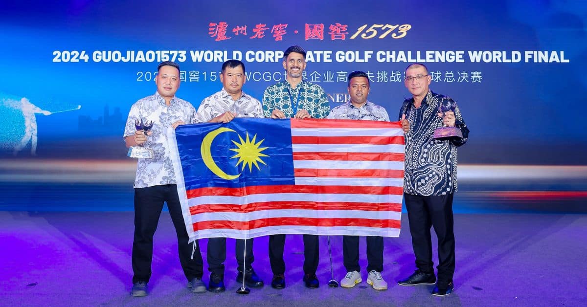 The Malaysian delegation holding their national flag at the WCGC 2024 World Final, celebrating their achievement.