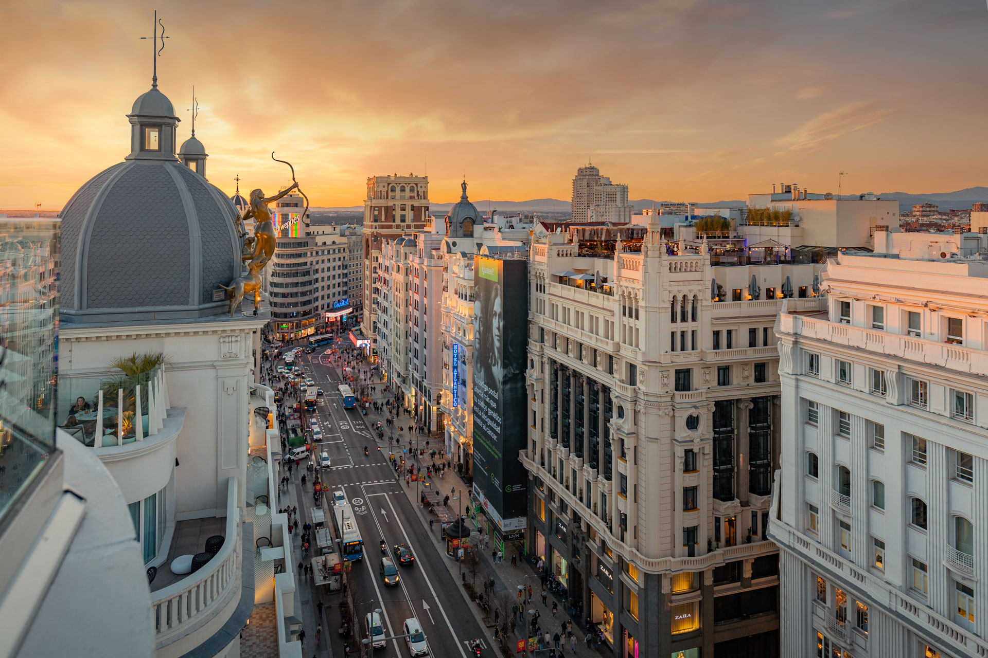 Aerial view of Gran Vía in Madrid at sunset, with the dome of the Metrópolis building in the foreground